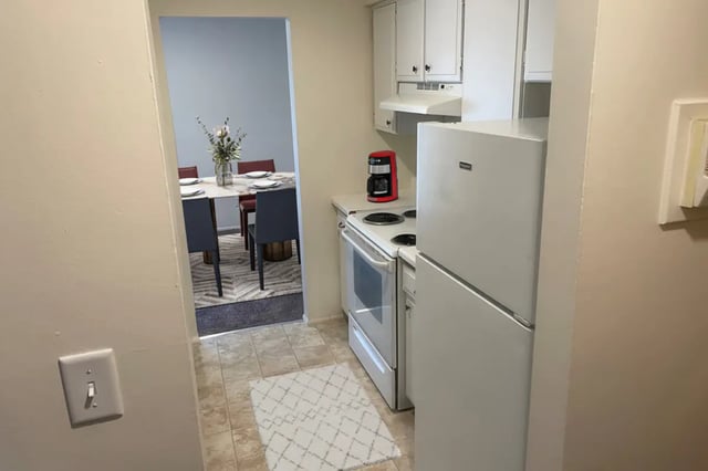 Fridge stove coffee maker dining table kitchen at East Knolls Apartment in East Lansing Student Accommodation