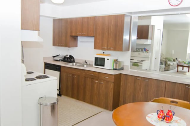 Wood cabinets sink microwave oven stove kitchen at East Knolls Apartment in East Lansing Student Accommodation