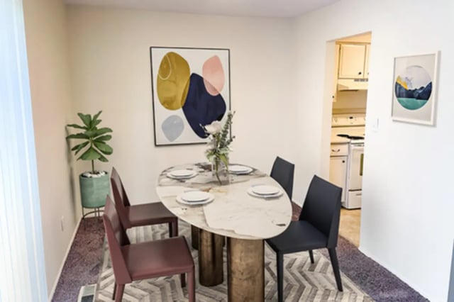 Dining table with chairs plant and abstract art Dining area at East Knolls Apartment in East Lansing Student Accommodation