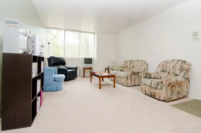 Armchairs and sofa near window and TV living room at East Knolls Apartment in East Lansing Student Accommodation