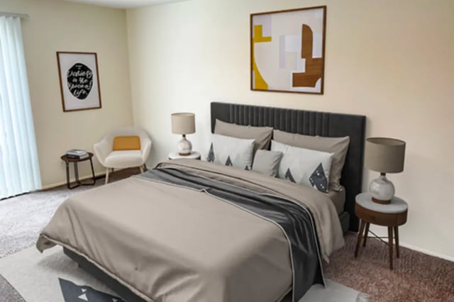 Bed with bedside tables lamps chairs art Bedroom at East Knolls Apartment in East Lansing Student Accommodation