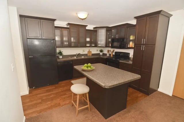 Dark cabinets refrigerator island and sink kitchen at Americana Apartments in East Lansing Student Accommodation