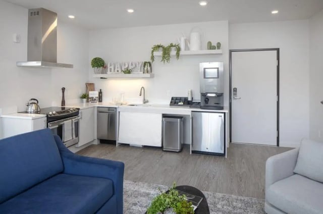 Blue couch white counters stainless steel appliances kitchen at Curry Court Apartments in Portland Student Accommodation