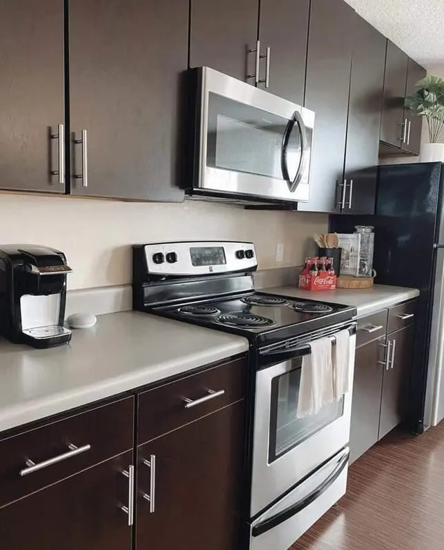 Modern kitchen with dark cabinets microwave stove refrigerator kitchen at The Ave at Norman Apartments in Norman Student Accommodation