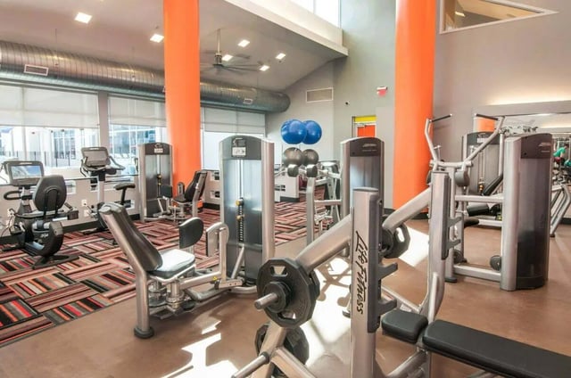 Gym equipment with colorful carpet and orange pillars gym at The Ave at Norman Apartments in Norman Student Accommodation
