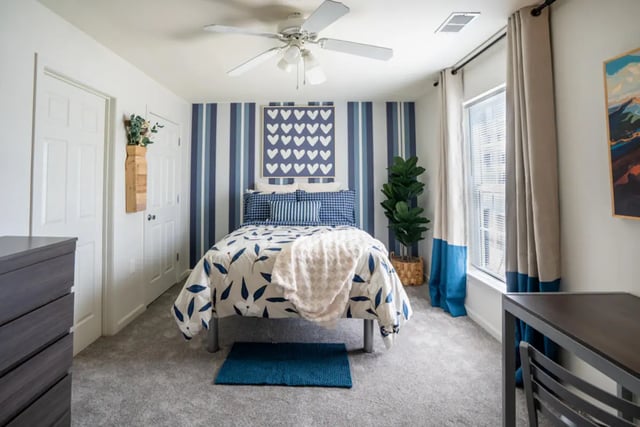 Bed with blue accents and blanket Bedroom at The Roost in Rexburg Student Accommodation
