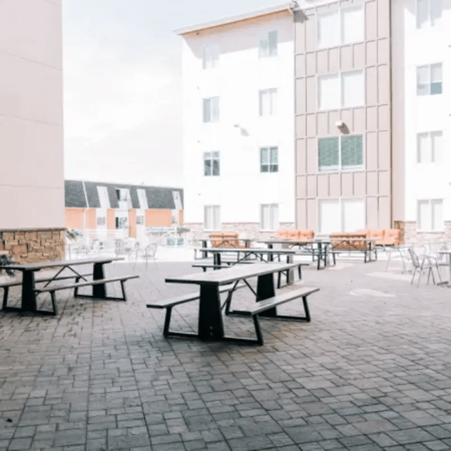 Picnic tables and orange benches courtyard exterior at Cedars Women's Housing in Rexburg Student Accommodation