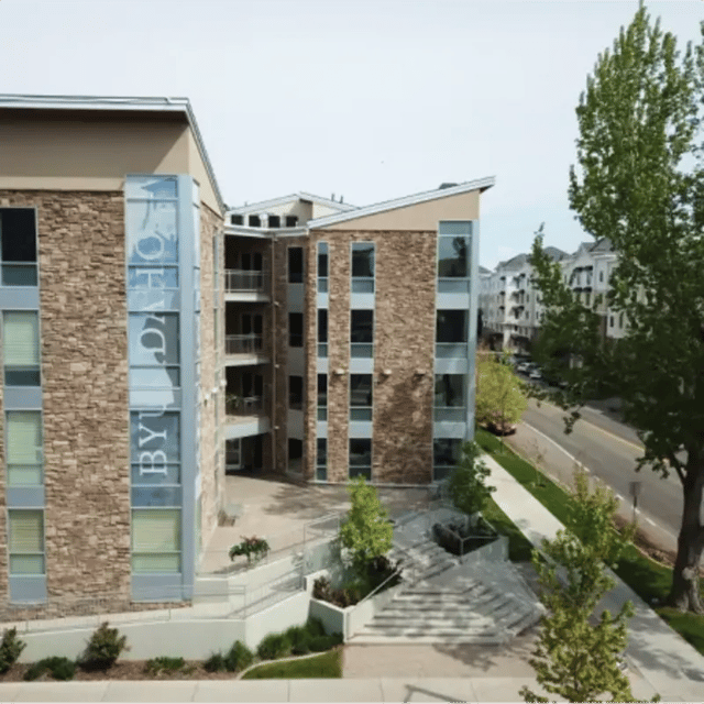 Stone building with windows and balconies exterior at Cedars Women's Housing in Rexburg Student Accommodation