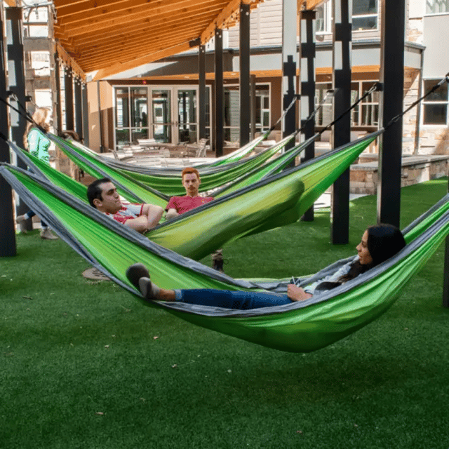 People relax in green hammocks outdoor area at Cedars Women's Housing in Rexburg Student Accommodation