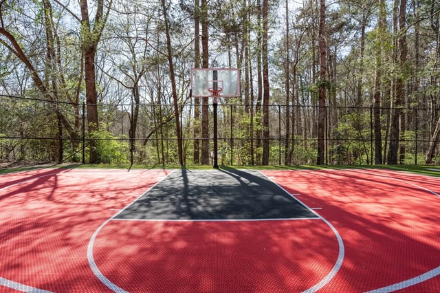 Red outdoor basketball court with trees playing area at The Redland Apartments in Athens Student Accommodation