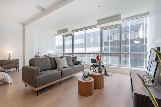 Gray couch wooden tables desk and windows living room at Atlas House Apartments in Los Angeles Student Accommodation