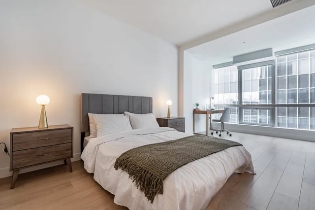 Bed desk and chair in bedroom with large window at Atlas House Apartments in Los Angeles Student Accommodation