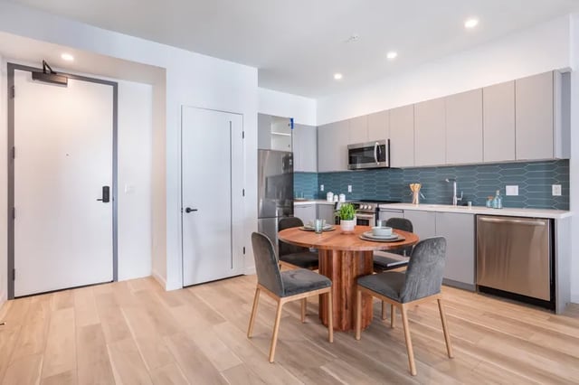 Dining table and chairs with kitchen appliances kitchen at Atlas House Apartments in Los Angeles Student Accommodation