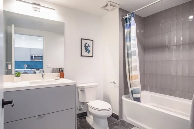 Vanity toilet bathtub shower curtain bathroom at Atlas House Apartments in Los Angeles Student Accommodation