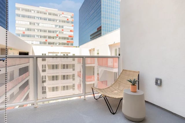 Woven chair, side table, potted plant balcony at Atlas House Apartments in Los Angeles Student Accommodation