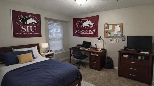 Bed desk chair flags and television Bedroom at 900 on Park Apartments in Carbondale Student Accommodation