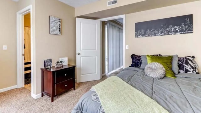 Bed with pillows dresser doorway and artwork bedroom at 900 on Park Apartments in Carbondale Student Accommodation