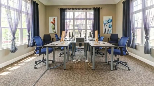 Computers and blue chairs in a study area at 900 on Park Apartments in Carbondale Student Accommodation