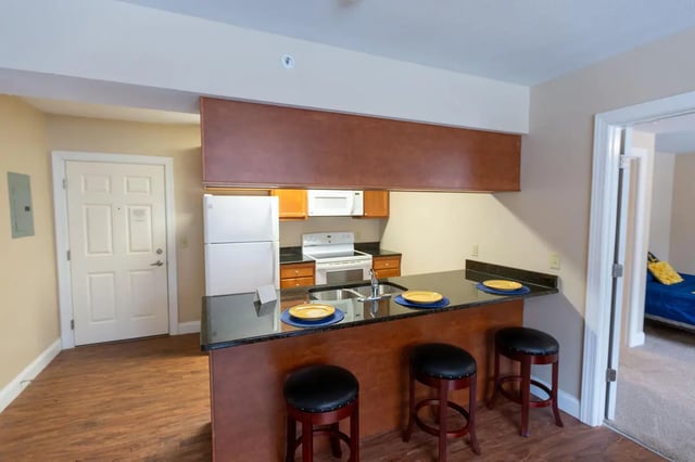 Kitchen counter with stools refrigerator stove and sink kitchen at Central Place in Morgantown Student Accommodation