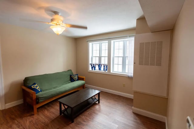 Green futon, dark coffee table, WVU decor, living room at Central Place in Morgantown Student Accommodation