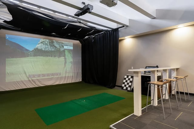 Golf simulator screen with bar stools playing area at Station 21 in West Lafayette Student Accommodation