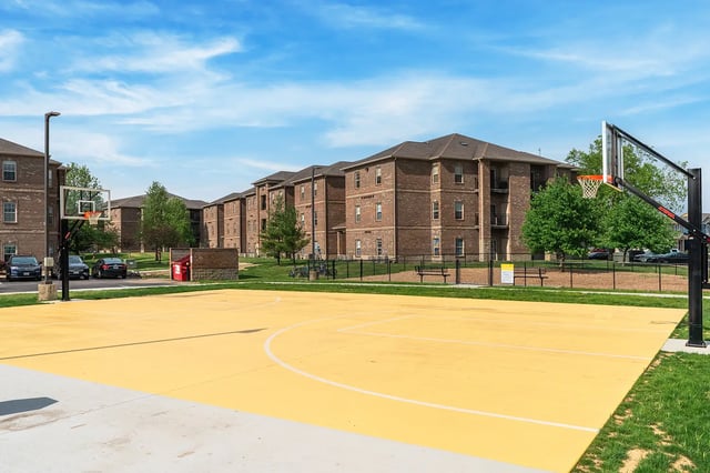 Yellow basketball court with hoop and brick buildings exterior at Station 21 in West Lafayette Student Accommodation