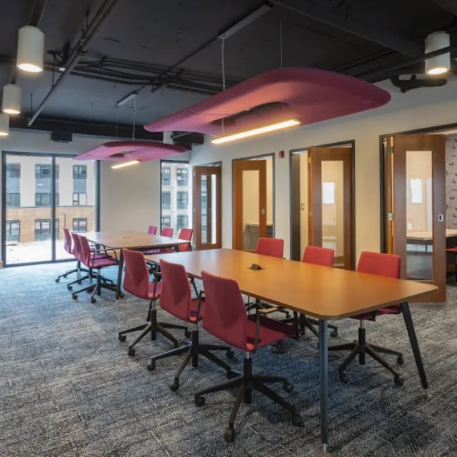 Conference tables and red chairs in meeting room at Apex Apartments in Rochester Student Accommodation
