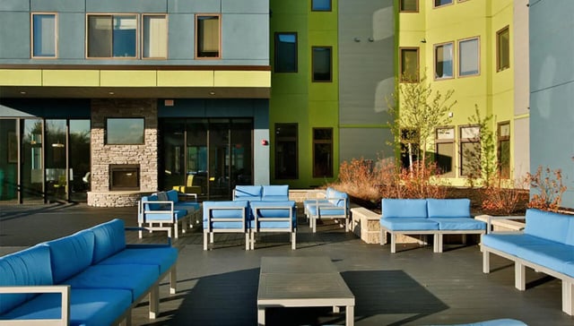 Blue sofas and tables on a patio exterior at Auden Albany in Albany Student Accommodation