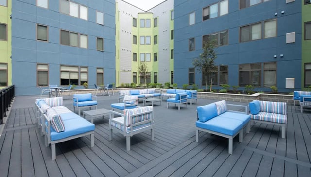 Blue upholstered sofas and lounge chairs outdoor seating area at Auden Albany in Albany Student Accommodation