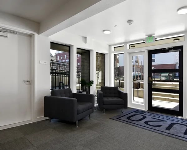 Two dark armchairs by large windows and door lobby at Juno Studios in Seattle Student Accommodation