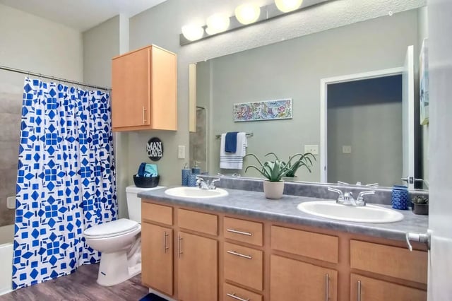 Double sink vanity toilet shower curtain bathroom at Fifty Twenty-Five Apartments in San Diego Student Accommodation