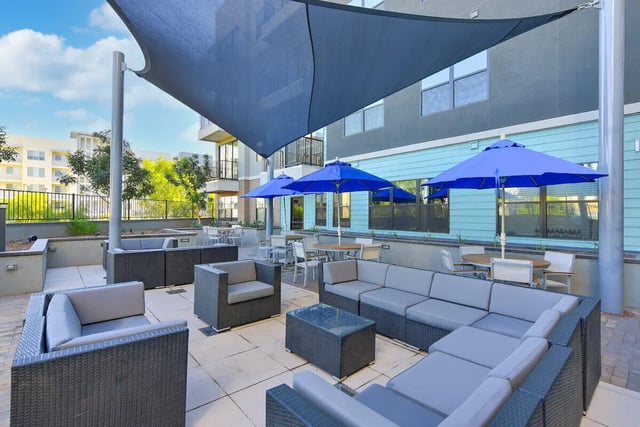 Wicker lounge furniture blue umbrellas outdoor dining living area at Park Place Tempe in Tempe Student Accommodation