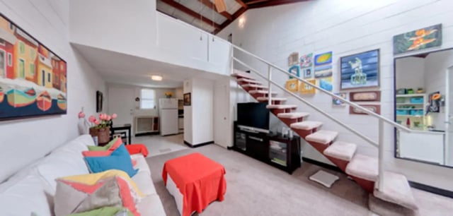 Sofa stairs TV artwork kitchen living room at Arbor Lofts in Gainesville Student Accommodation