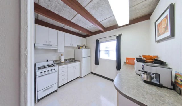 White cabinets stove refrigerator sink countertop kitchen at Arbor Lofts in Gainesville Student Accommodation