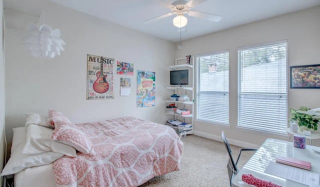 Bed with pink patterned comforter and study desk Bedroom at Heritage Oaks Luxury Apartments in Gainesville Student Accommodation
