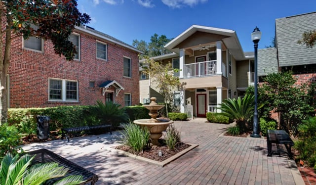 Fountain benches and brick buildings exterior at Heritage Oaks Luxury Apartments in Gainesville Student Accommodation