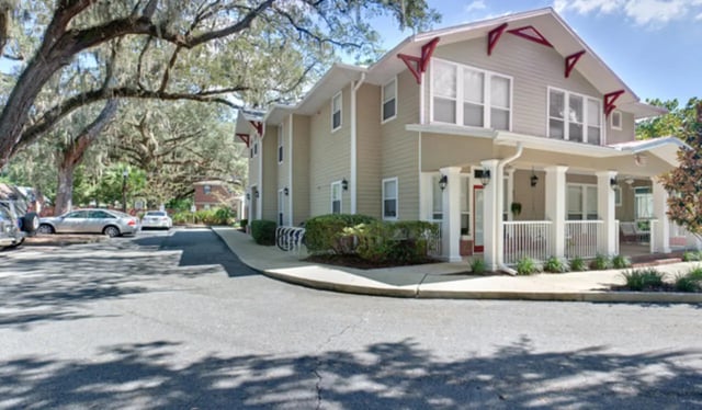 Apartment building with porch cars and trees exterior at Heritage Oaks Luxury Apartments in Gainesville Student Accommodation