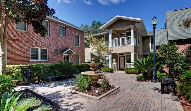 Brick building fountain benches and greenery exterior at Heritage Oaks Luxury Apartments in Gainesville Student Accommodation