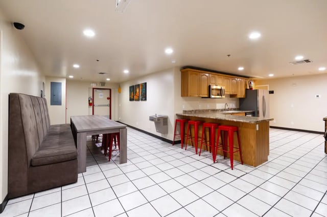 Bench table with red stools and kitchen area common room at Dixie Cove Student Housing in St. George Student Accommodation