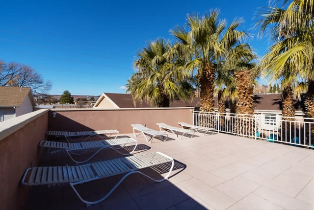 Lounge chairs on a patio with palm trees exterior at Dixie Cove Student Housing in St. George Student Accommodation