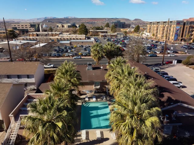 Palm trees surround bright blue pool with lounge chairs exterior at Dixie Cove Student Housing in St. George Student Accommodation
