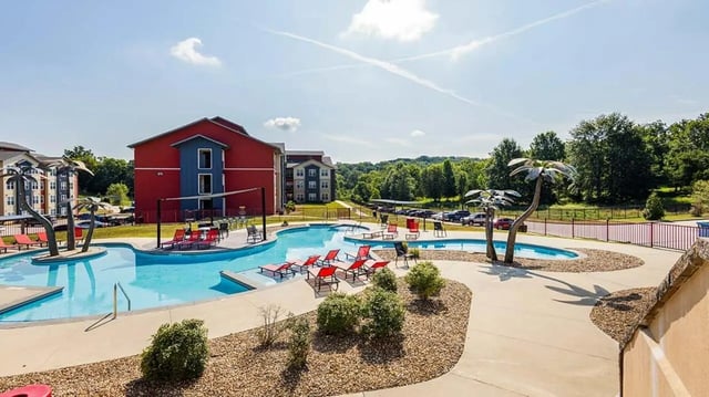 Pool with palm trees lounge chairs and buildings exterior at Hawks Landing Apartments in Cape Girardeau Student Accommodation