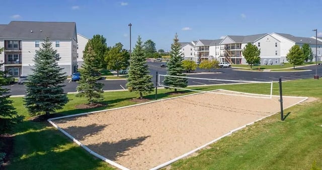 Sand volleyball court with apartment buildings exterior at Village at Bluegrass in Mount Pleasant Student Accommodation