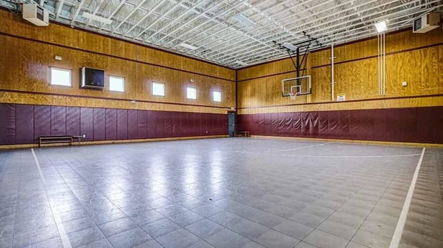 Indoor basketball court with padded walls and bleachers recreational area at Village at Bluegrass in Mount Pleasant Student Accommodation