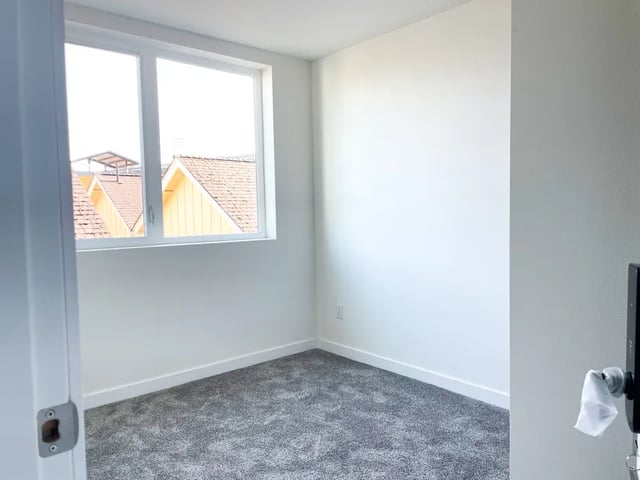 Empty room gray carpet white walls window study area at Husky Urban Living in Seattle Student Accommodation