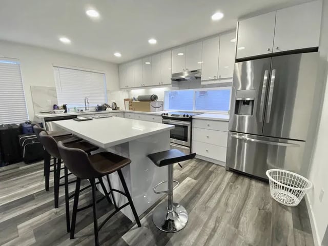 White modern kitchen island with stools and fridge kitchen at Husky Urban Living in Seattle Student Accommodation