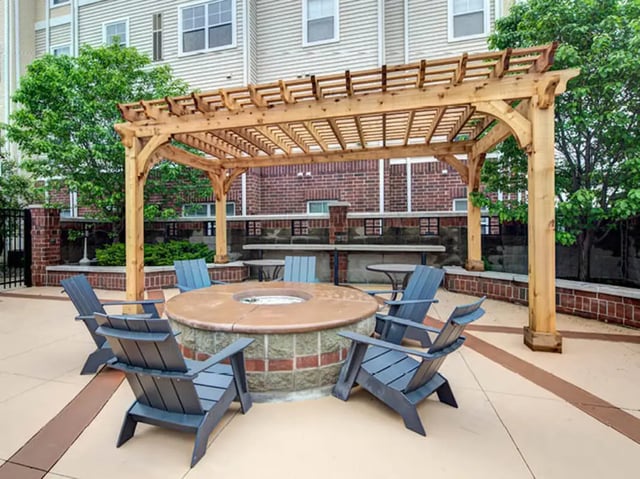 Fire pit with chairs under pergola outdoor living space at University Commons