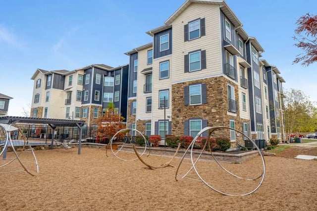 Apartment buildings with playground equipment exterior at The Den Apartments in Berkeley Student Accommodation