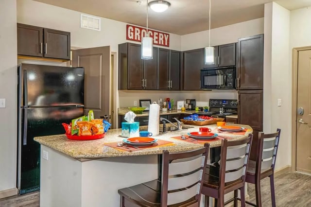 Kitchen with dark cabinets refrigerator and island kitchen at The Den Apartments in Berkeley Student Accommodation