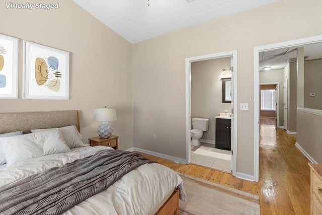 Bed with artwork and open bathroom door bedroom at Stadium Properties Apartments in Tallahassee Student Accommodation